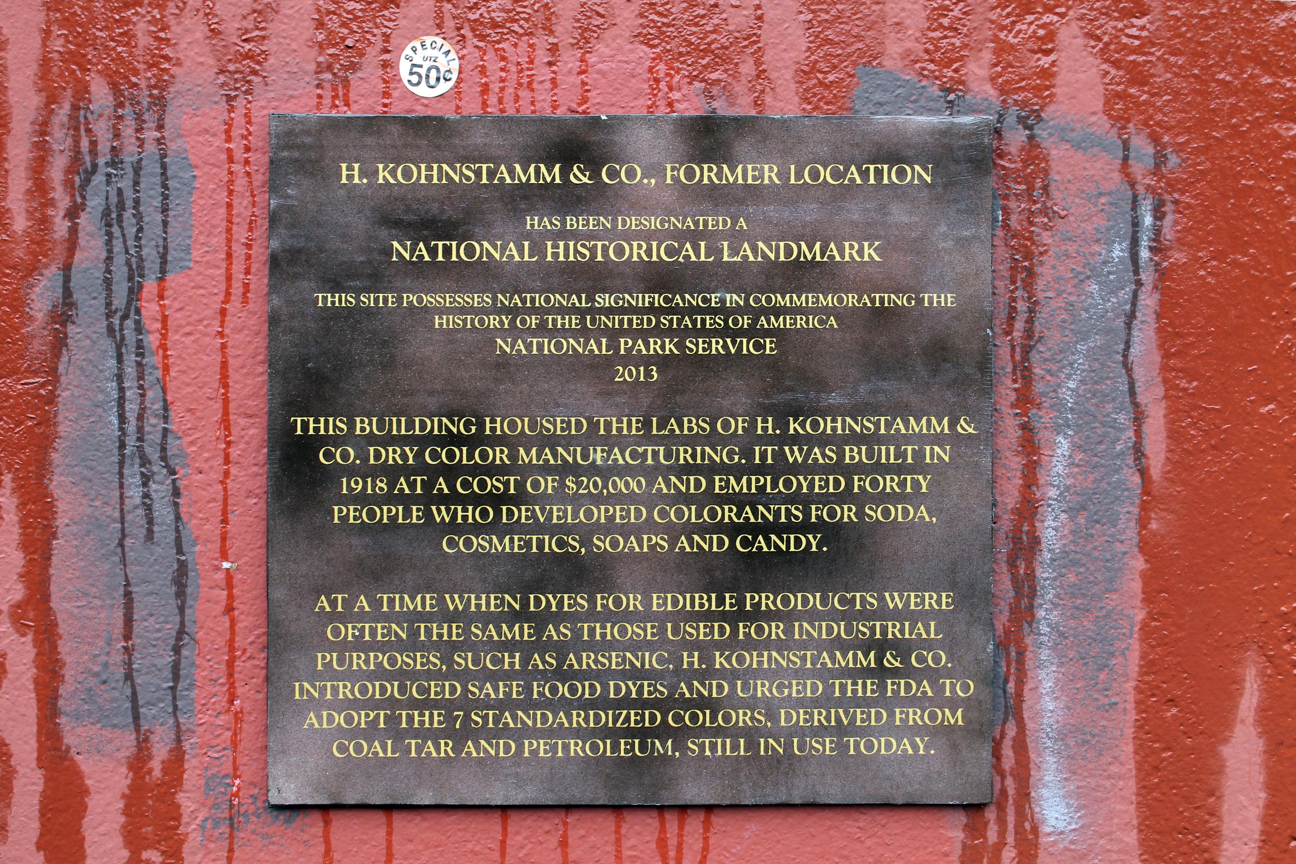 Photograph of a handmade landmark plaque hanging on a concrete wall
